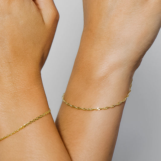 Mano de mujer usando pulsera de tejido Singapur en oro amarillo de 18 quilates en Joyería Caracas. 
