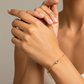 Mano de mujer usando una pulsera de enlace único en oro amarillo de 18 quilates de Joyería Caracas. 