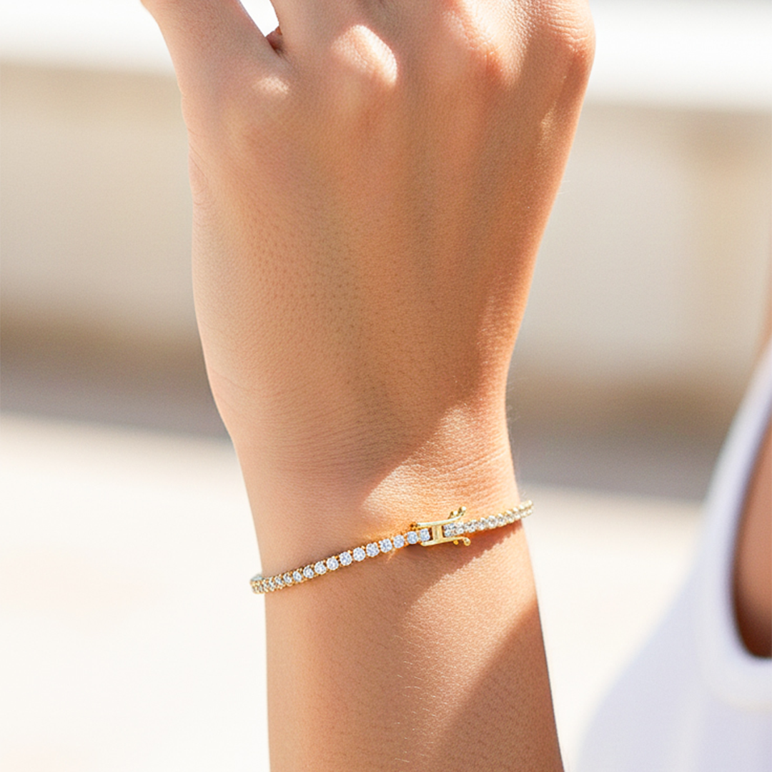 Mano de una modelo usando una pulsera tennis en oro amarillo con cristales de Joyería Caracas.