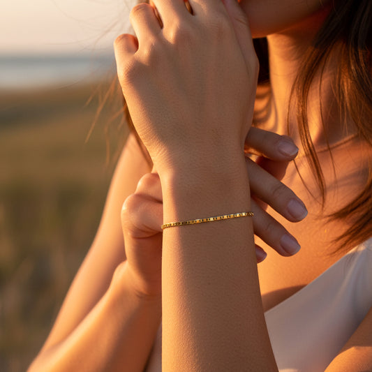 Mano de mujer usando una pulsera tejido escalera plana lisa en oro amarillo de 18 quilates de Joyería Caracas. 