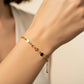 Mano de mujer usando una pulsera con herrajes de infinitos con corazón y esferas facetadas en oro amarillo de 18 quilates de Joyería Caracas. 
