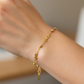 Mano de mujer usando una pulsera con infinitos y esferas facetadas en oro amarillo de 18 quilates de Joyería Caracas. 