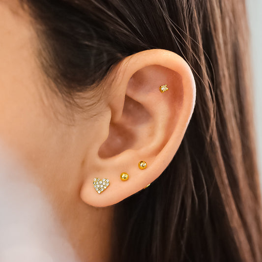 Oreja de mujer con topito en forma de corazón en oro amarillo de 18 quilates con cristales de color blanco, hechos en Joyería Caracas. 