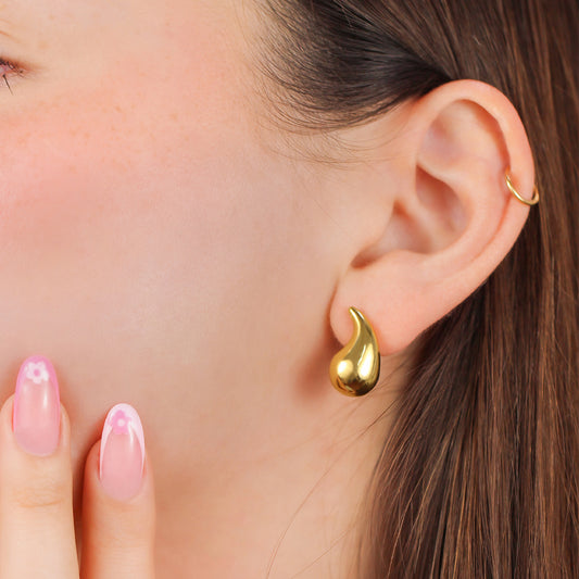 Oreja de mujer con topito en forma de gota en oro amarillo de 18 quilates, hechos en Joyería Caracas. 