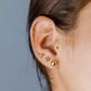 Oreja de mujer con topito en forma de corazón en oro amarillo de 18 quilates con 3 cristales de color rojo, hechos en Joyería Caracas. 