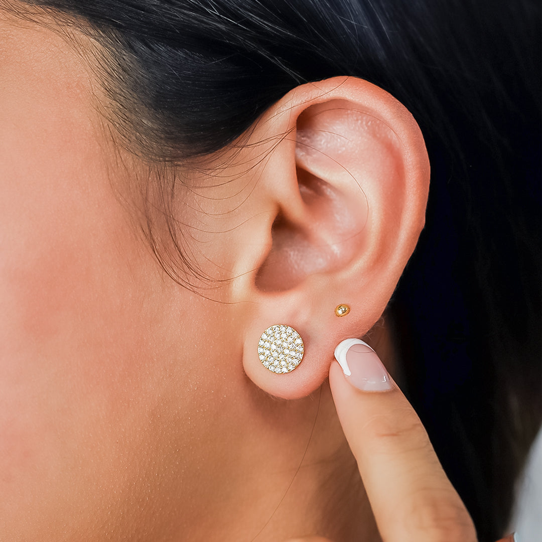 Oreja de mujer con topito en forma circular en oro amarillo de 18 quilates, con cristales de color blanco, hechos en Joyería Caracas. 
