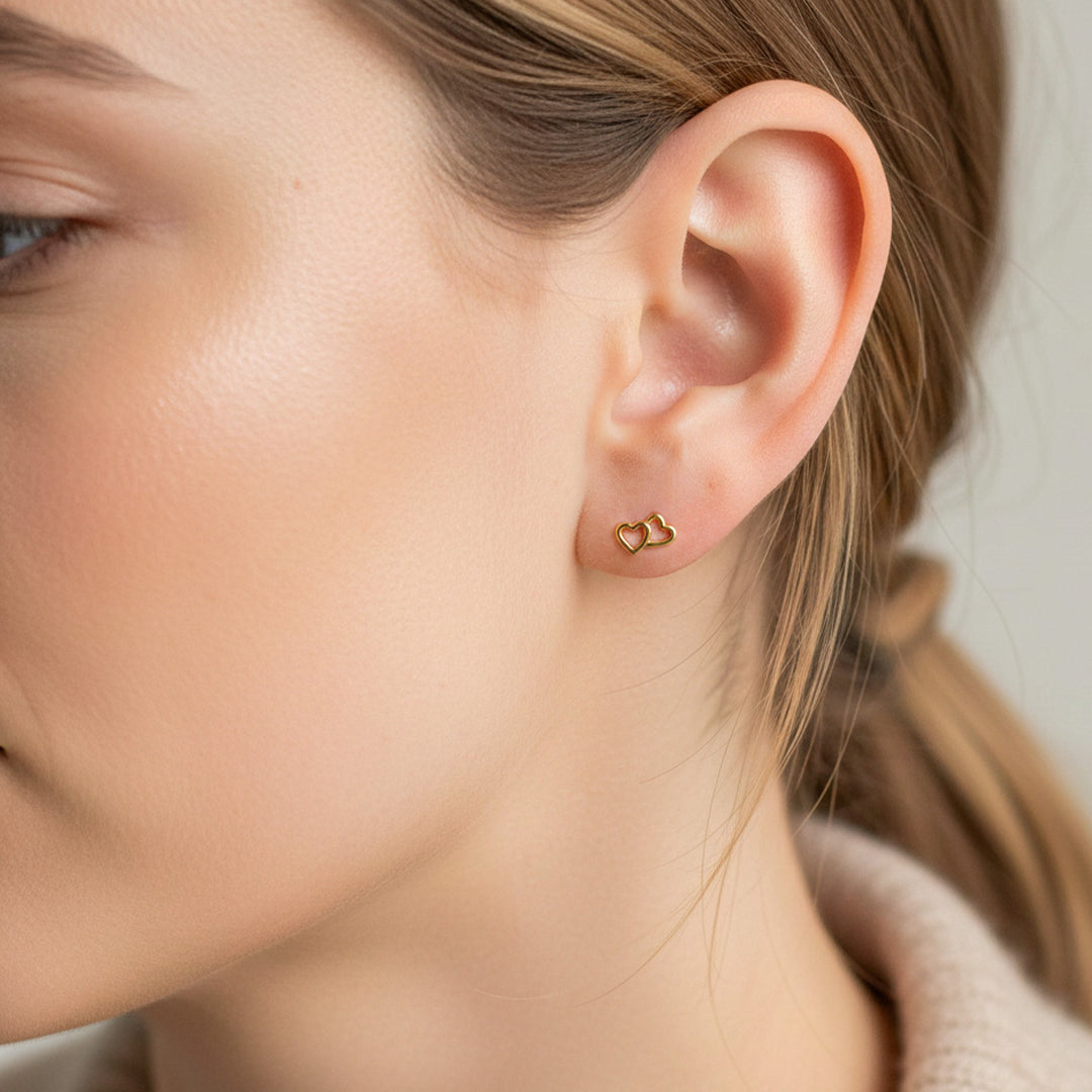 Oreja de modelo usando un topito en forma de corazón doble liso en oro amarillo de 18 quilates de Joyería Caracas. 