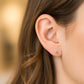 Oreja de modelo usando un topito en forma de flor de 6 pétalos en oro amarillo de 18 quilates con cristal de color blanco de Joyería Caracas. 