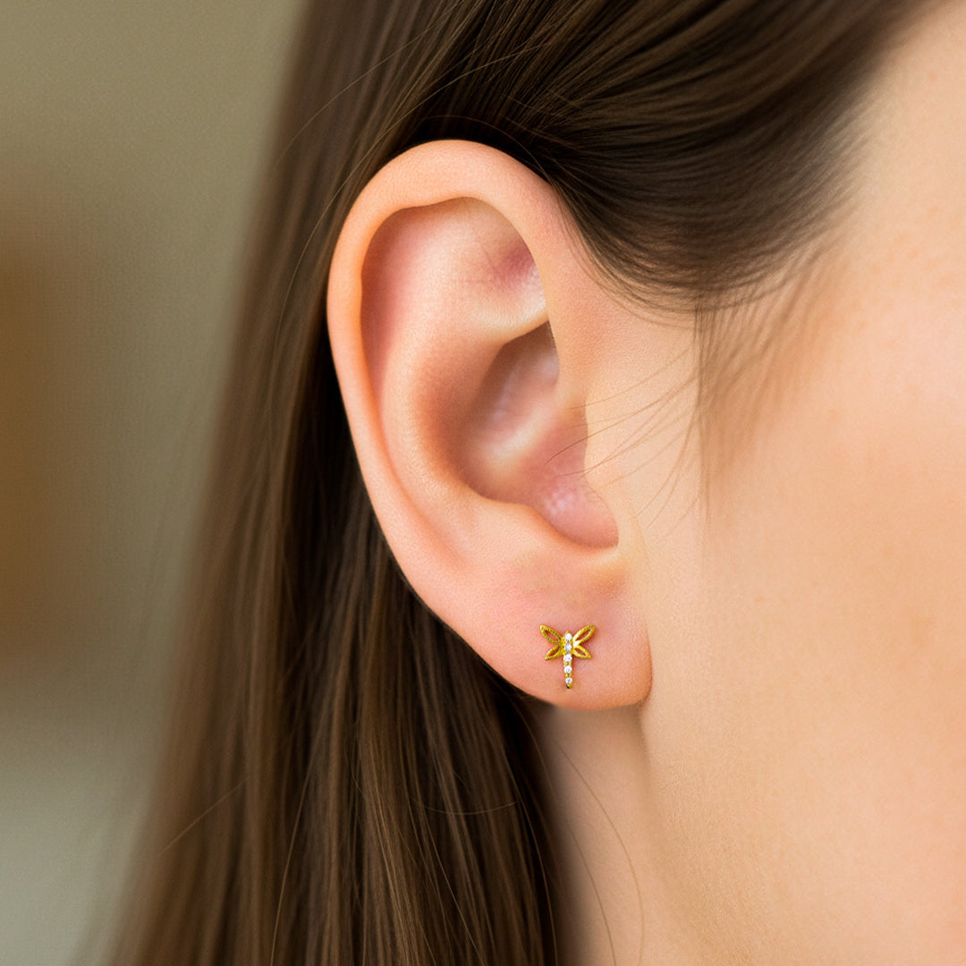 Oreja de modelo usando un topito en forma de libélula en oro amarillo de 18 quilates de Joyería Caracas. 
