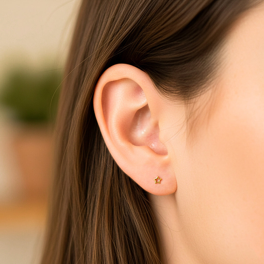 Oreja de modelo usando un topito en forma de estrella en oro amarillo de 18 quilates de Joyería Caracas.