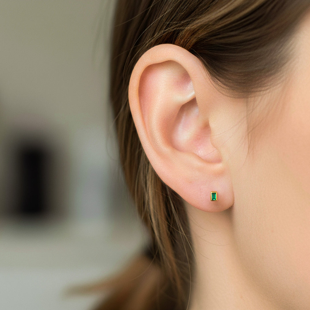 Oreja de modelo usando unos topitos en oro amarillo de 18 quilates con Esmeraldas de Joyería Caracas. 