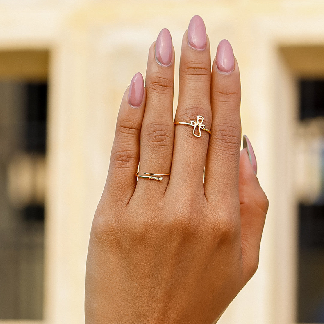 Mano de mujer usando anillo con un ángel en el centro en oro amarillo de 18 quilates, hecho en Joyería Caracas. 