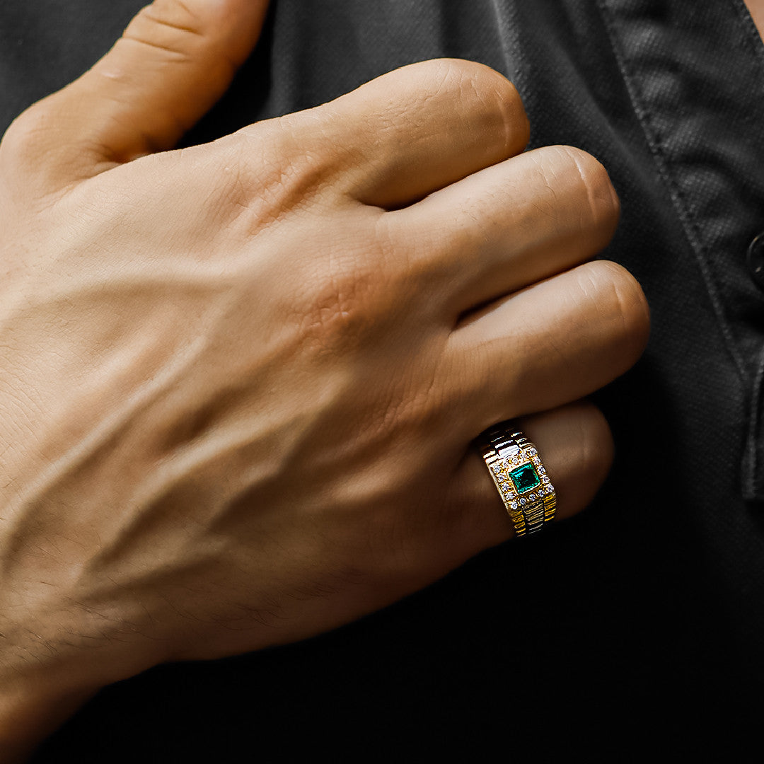 Mano de hombre con anillo Armis en oro amarillo y blanco de 18 quilates con esmeralda de color verde en el centro y cristales de color blanco alrededor, hecho en Joyería Caracas. 