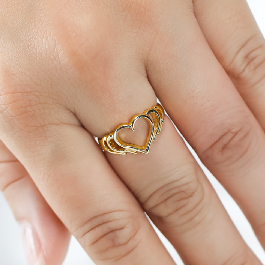 Mano de mujer con anillo en forma de corazón calado en oro amarillo de 18 quilates, hecho en Joyería Caracas. 