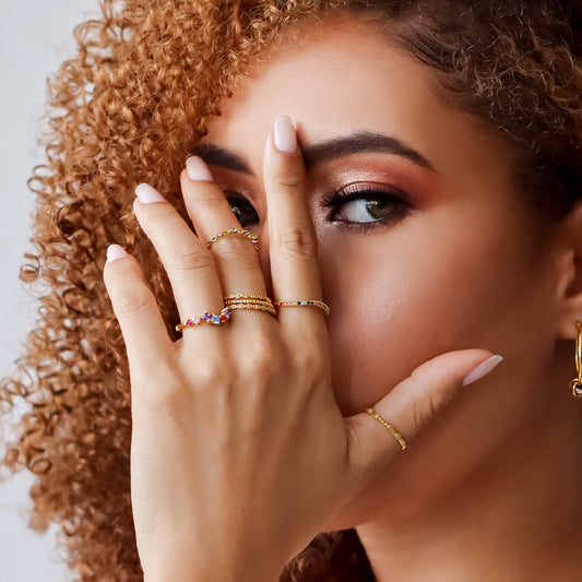 Mano de mujer con anillo en oro amarillo de 18 quilates con cristales de distintos colores, hecho en Joyería Caracas. 