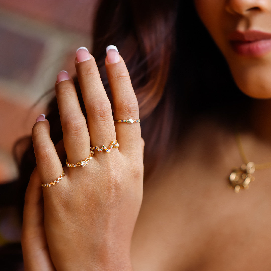 Mano de mujer con anillo en oro amarillo de 18 quilates con cristales de distintos colores, hecho en Joyería Caracas. 