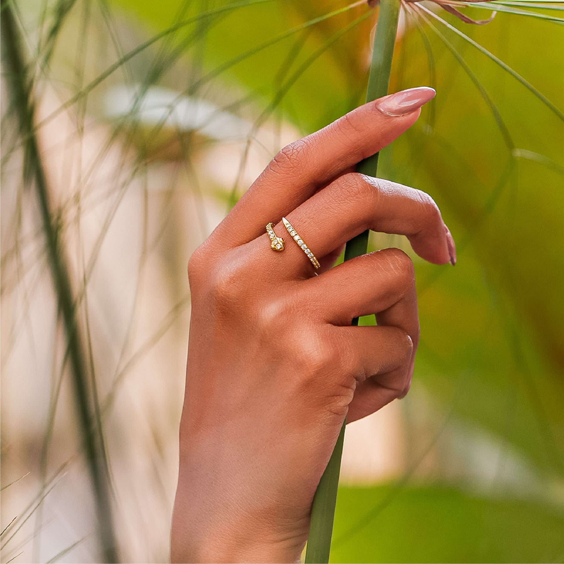 Mano de mujer con anillo en forma de serpiente en oro amarillo de 18 quilates con cristales de color blanco, hecho en Joyería Caracas. 