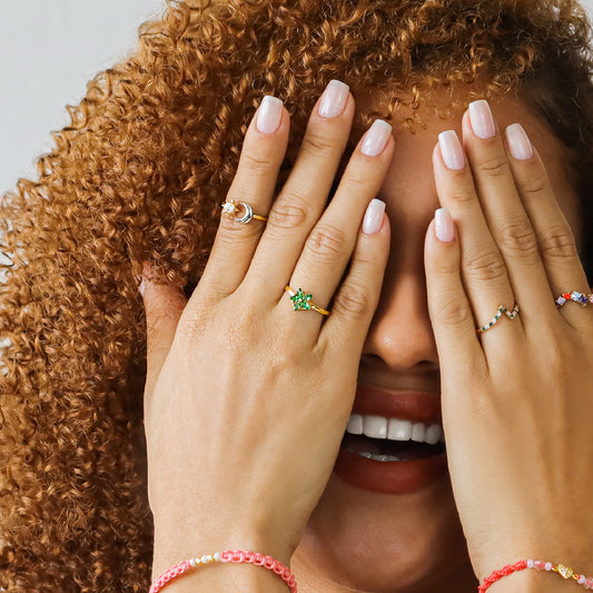 Mano de mujer con anillo en forma de sol y luna en tres oros de 18 quilates con cristal de color blanco, hecho en Joyería Caracas. 