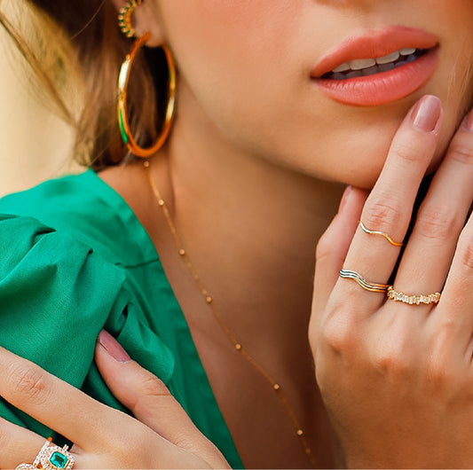 Mano de mujer con anillos en forma de curva en oro amarillo, blanco y rosa de 18 quilates, hecho en Joyería Caracas. 