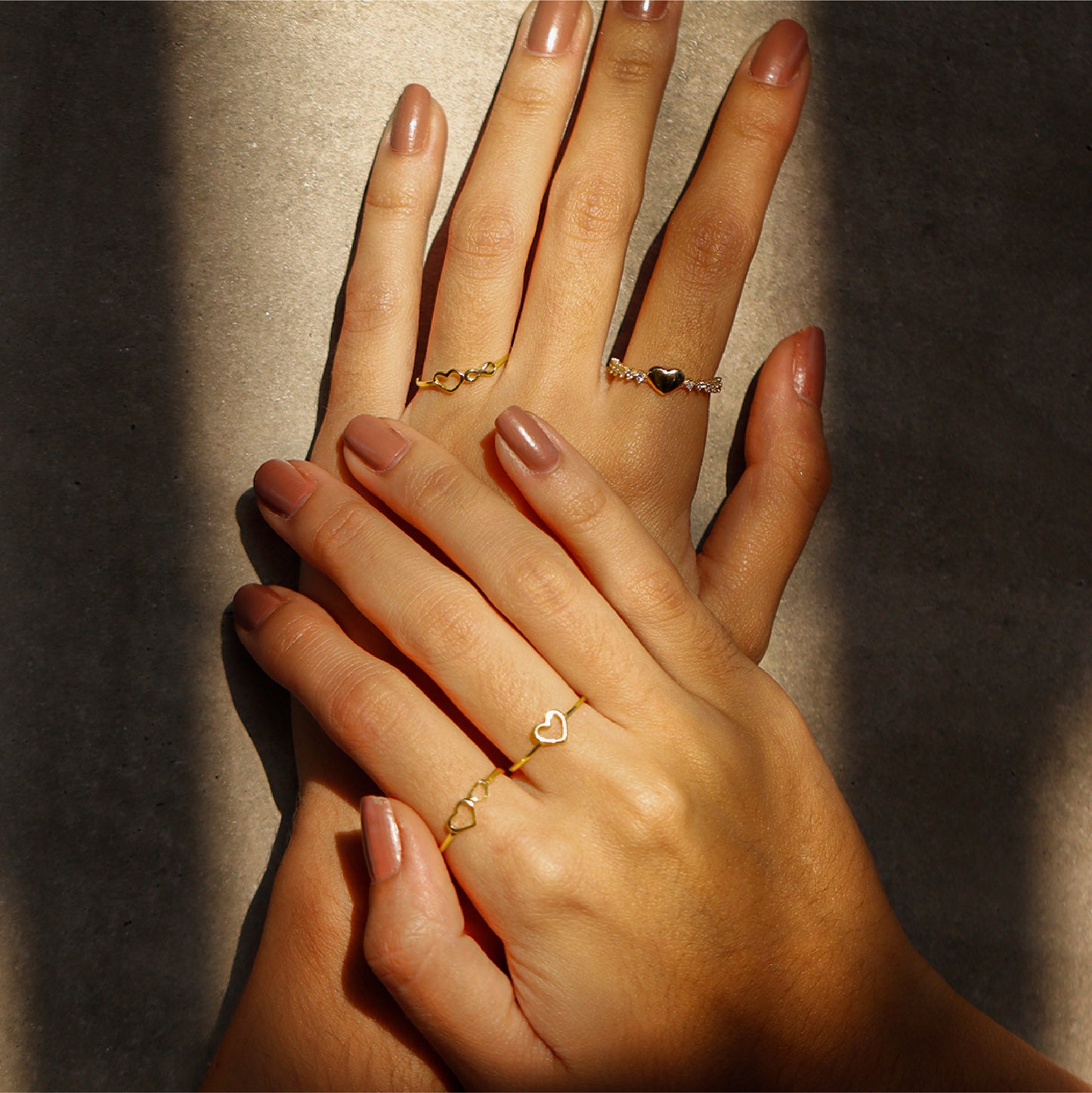 Mano de mujer usando anillo con 2 corazones en oro amarillo de 18 quilates, hecho en Joyería Caracas. 