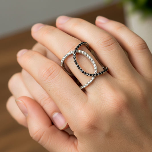Mano de mujer usando un anillo en oro blanco de 18 quilates con cristales de color blanco y negro de Joyería Caracas. 