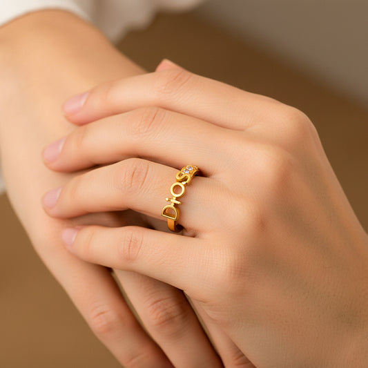 Mano de mujer usando un anillo con la palabra Dios en el centro en oro amarillo de 18 quilates con cristales de color blanco de Joyería Caracas. 