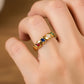 Mano de modelo usando un anillo con diseño de onda en oro amarillo de 18 quilates con 4 cristales en corte Marquiz de distintos colores de Joyería Caracas. 