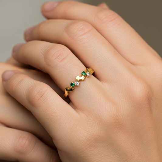 Mano de mujer usando un anillo con formas de ramas en oro amarillo de 18 quilates y Esmeraldas de Joyería Caracas. 