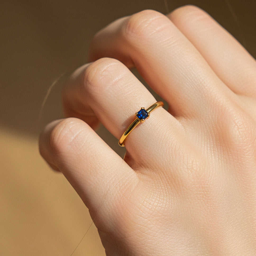 Mano de modelo usando un anillo en oro amarillo de 18 quilates con cristal azul de Joyería Caracas. 