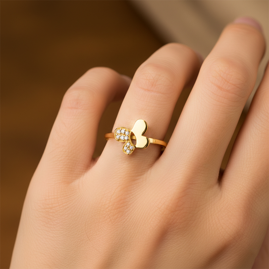 Mano de mujer usando un anillo con forma de mariposa en el centro en oro amarillo de 18 quilates con cristales de color blanco de Joyería Caracas. 