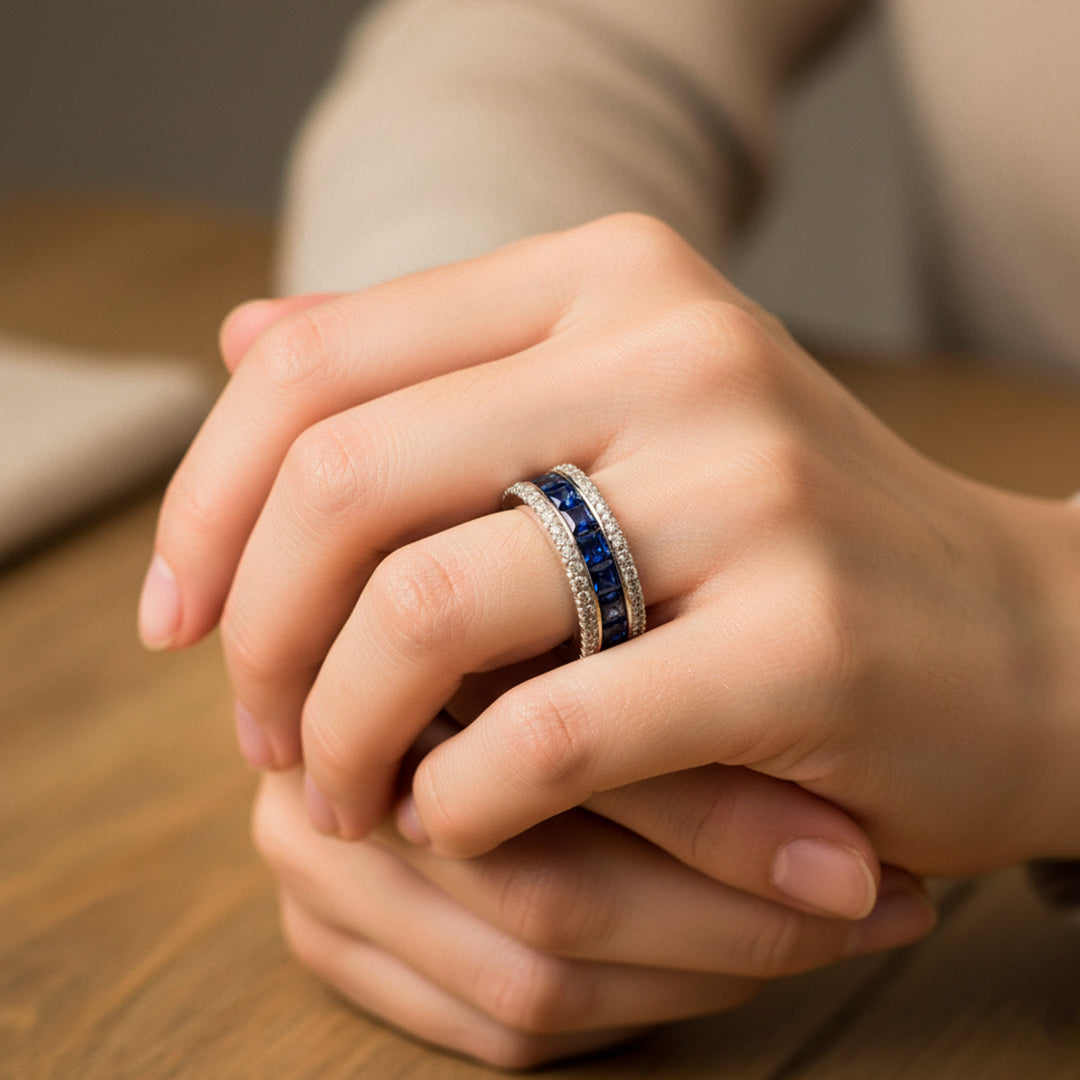 Mano de mujer usando un anillo en oro blanco de 18 quilates con cristales de color azul y blanco de Joyería Caracas. 