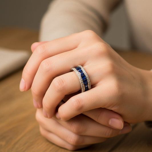 Mano de mujer usando un anillo en oro blanco de 18 quilates con cristales de color azul y blanco de Joyería Caracas. 