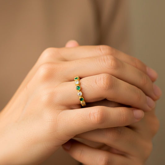 Mano de mujer usando un anillo caterpillar en oro amarillo de 18 quilates con cristales de color blanco y verde de Joyería Caracas. 