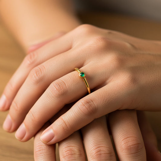 Mano de mujer usando un anillo con forma de círculo en el centro en oro amarillo de 18 quilates con Esmeralda redonda de color verde de Joyería Caracas.
