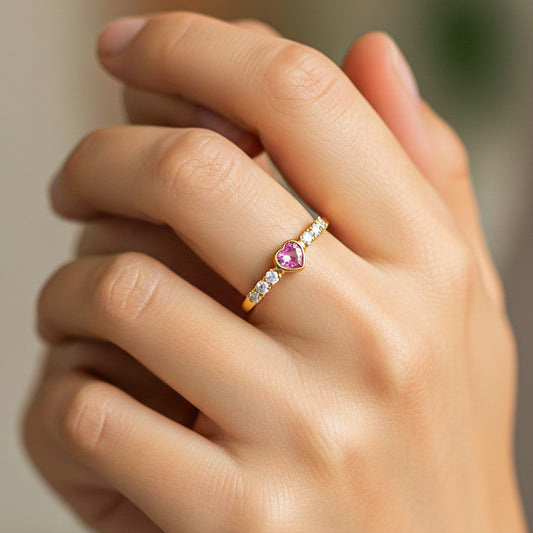 Mano de modelo usando un anillo en oro amarillo de 18 quilates con cristal en forma de corazón rosa y cristales alrededor de Joyería Caracas. 