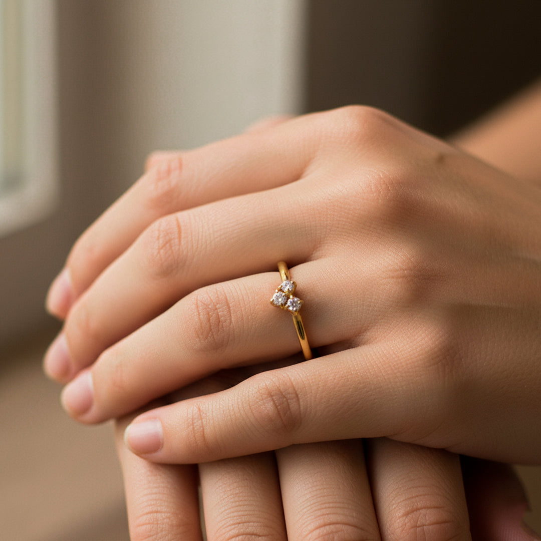 Mano de mujer usando un anillo en oro amarillo con forma de corazón en el centro de 18 quilates con 3 cristales de color blanco de Joyería Caracas. 