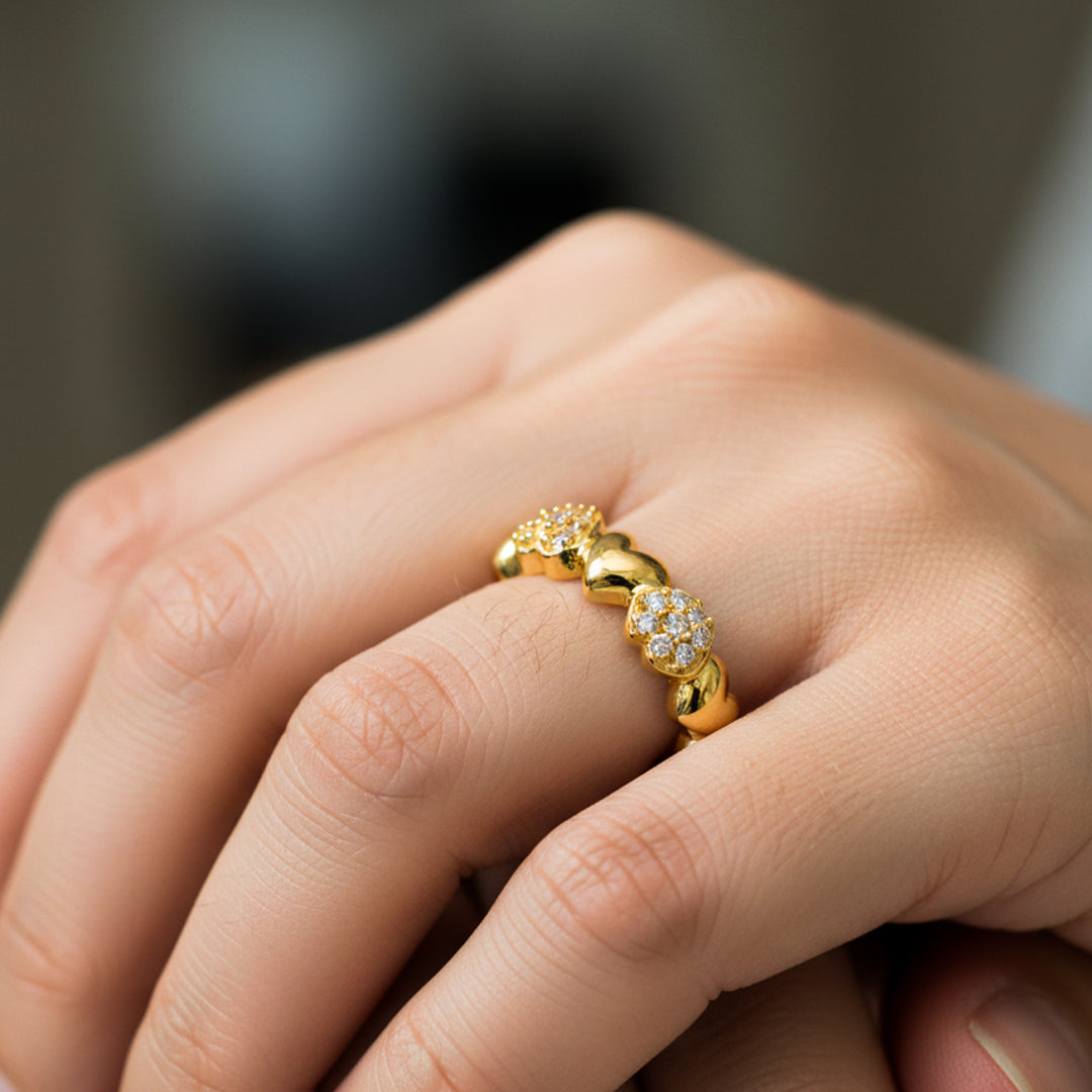 Mano de mujer usando anillo con forma de corazones en oro amarillo de 18 quilates con cristales de color blanco de Joyería Caracas. 