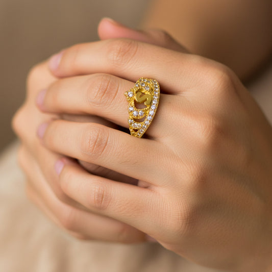 Mano de mujer usando un anillo en forma de corona con letra en oro amarillo de 18 quilates con cristales de color blanco de Joyería Caracas. 
