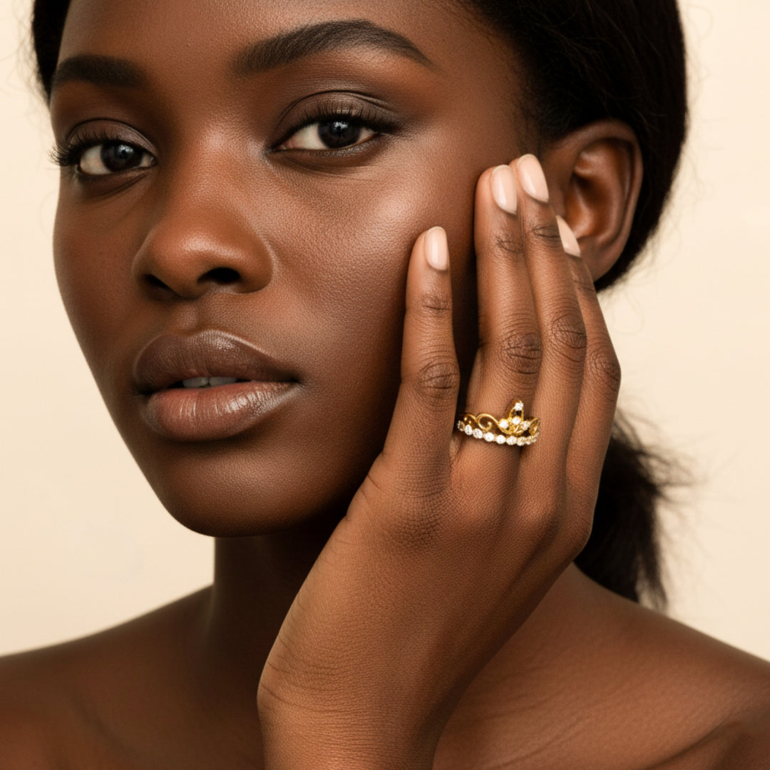 Mano de mujer usando un anillo en forma de corona en oro amarillo de 18 quilates con cristales de color blanco de Joyería Caracas. 