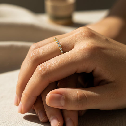 Mano de mujer usando un anillo en oro amarillo de 18 quilates con cristales de color blanco de Joyería Caracas. 