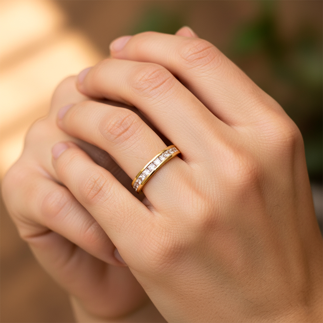 Mano de mujer usando un anillo en oro amarillo de 18 quilates con cristales cuadrados de color blanco de Joyería Caracas. 