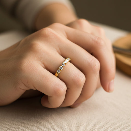 Mano de mujer usando un anillo pisargolla en oro amarillo de 18 quilates con cristales de color blanco de Joyería Caracas. 