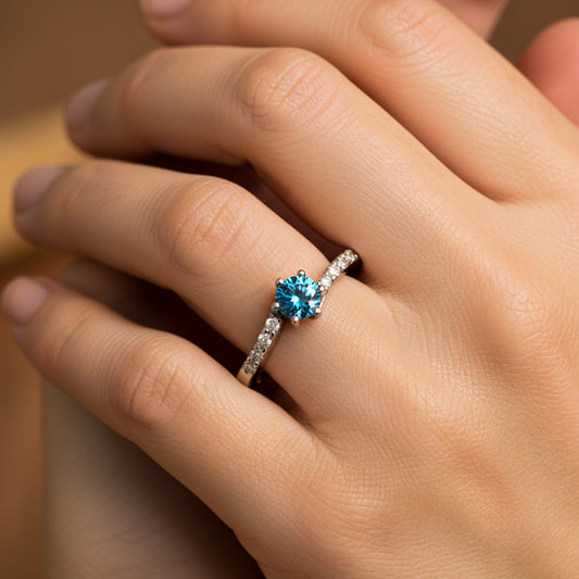 Mano de mujer usando anillo diseño deep navy blue en oro blanco de 18 quilates con Diamante natural de color azul y Diamantes de color blanco alrededor de Joyería Caracas. 