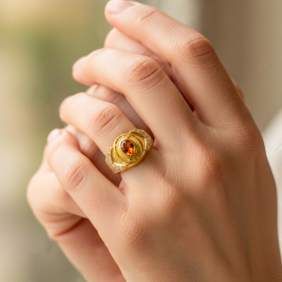 Mano de modelo usando un anillo de grado en oro amarillo de 18 quilates con Topacio en el centro y cristales de Joyería Caracas. 