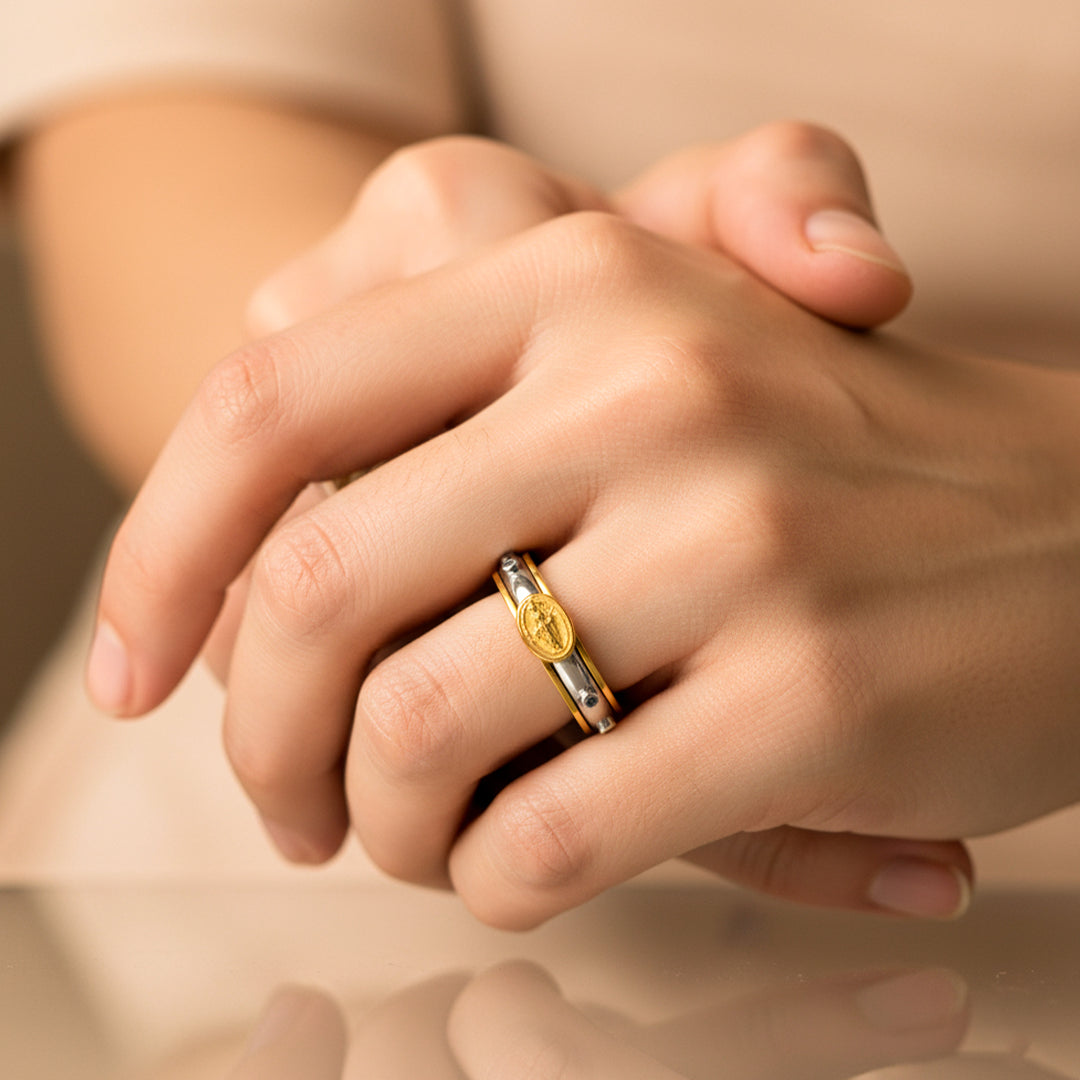 Mano de mujer usando un anillo denario con movimiento bicolor en oro de 18 quilates de Joyería Caracas. 