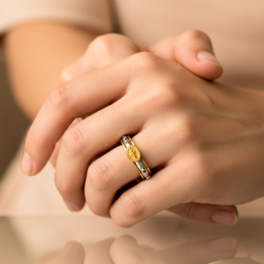 Mano de mujer usando un anillo denario con movimiento bicolor en oro de 18 quilates de Joyería Caracas. 
