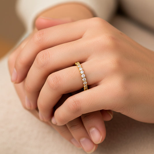 Mano de mujer usando un anillo sin fin en oro amarillo de 18 quilates con Diamantes de color blanco alrededor de Joyería Caracas. 