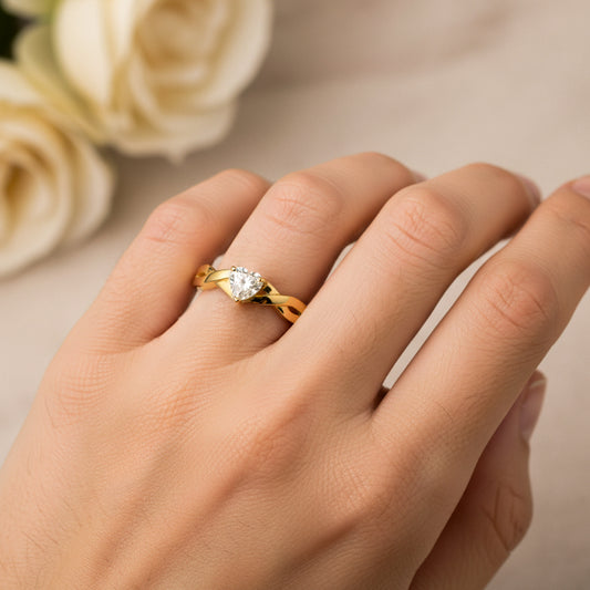 Mano de mujer usando un anillo en oro amarillo de 18 quilates entrelazado con Diamante en forma de corazón en el centro de Joyería Caracas. 
