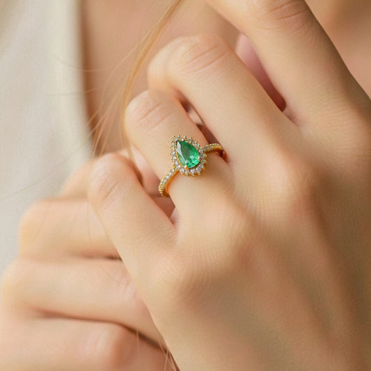 Mano de modelo usando un anillo en oro amarillo de 18 quilates con Esmeralda en forma de gota y cristales alrededor de Joyería Caracas. 