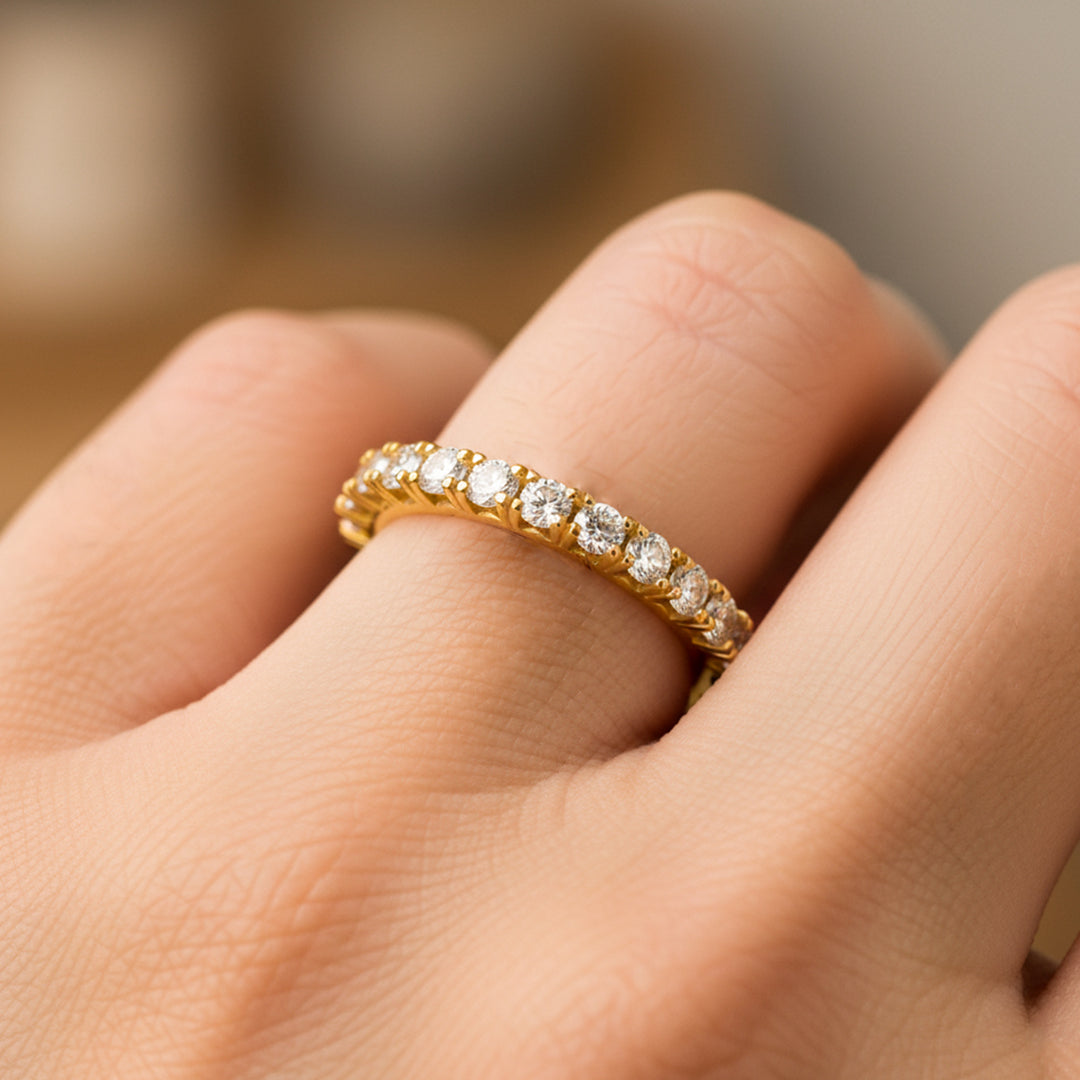 Mano de mujer usando un anillo en oro amarillo de 18 quilates con cristales de color blanco alrededor de Joyería Caracas. 